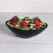 An Elite Global Solutions Moderne black melamine bowl filled with salad, strawberries, and lettuce.