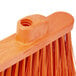 A close up of a Carlisle medium duty broom head with orange flagged bristles.