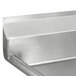 A stainless steel Advance Tabco four compartment sink with two drainboards on a metal surface.