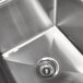 A stainless steel Advance Tabco four compartment commercial sink with two drainboards and a sink drain.