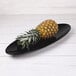 An Elite Global Solutions Moderne black melamine oblong platter with a pineapple on it.