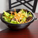 A bowl of salad with carrots and chicken in a Fineline black plastic bowl.