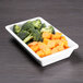A white Elite Global Solutions rectangular melamine bowl filled with broccoli and carrots.
