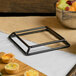 A Elite Global Solutions rubber coated steel stand with a tray of fruit and a bowl of fruit on a table.