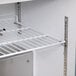 A white metal shelf with a handle on a white wall.