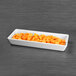 A white rectangular dish with diced orange fruit.