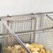 A Cooking Performance Group fryer basket of french fries sitting on a counter.