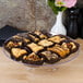 A Fineline clear plastic cake stand holding pastries on a table.