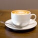 A white porcelain cup of coffee with a saucer and spoon.