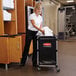A woman pushing a Rubbermaid laundry cart.