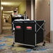 A black Rubbermaid laundry cart in a hotel hallway.