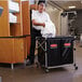 A man putting a white towel on a black Rubbermaid laundry cart.