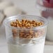 A clear Fabri-Kal plastic cup filled with yogurt and granola.