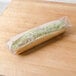 A sandwich wrapped in LK Packaging plastic on a wooden surface.
