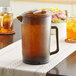 A brown glass GET pitcher with a lid on a table.