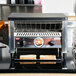 A Nemco conveyor toaster with bread on it.
