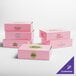 A close-up of a pink customizable cake box with black text on it.