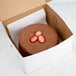 A 9" x 9" x 5" white cake box with a chocolate cake and strawberries on top.