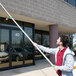 A man in a white shirt using an Unger TelePlus pole to clean the outside of a building.