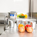 A Vollrath Redco King Kutter manual food processor with a clamp base and stainless steel cones on a counter with a red onion.