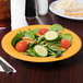 A plate of salad with cucumbers, tomatoes, and carrots in a yellow melamine bowl.