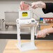 A person using a Weston Manual Meat Tenderizer to tenderize meat.