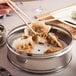 A person using Town stainless steel dim sum steamer to pick up a dumpling with chopsticks.