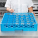 A woman in a blue apron using a Carlisle blue glass rack to hold clear glasses.