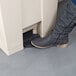 A person's foot stepping into a Rubbermaid rectangular step-on trash can.