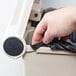 A hand putting a black bag in a Rubbermaid beige rectangular step-on trash can.