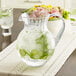 A clear GET Tahiti pitcher of water with ice and cucumber slices.