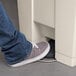 A person's foot stepping on a Rubbermaid mobile step-on container pedal.