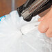 A hand using C-ring pliers to attach a plastic bag.