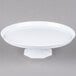 A Fineline white pedestal cake stand with a white plate on a pedestal.