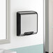A Bobrick silver and black stainless steel wall-mounted hand dryer.