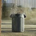 A Rubbermaid gray plastic utility trash can with a black lid.