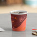 A Choice coffee cup filled with brown liquid on a table.