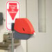 A red and grey Turn-O-Matic D900 Take a Number dispenser with a sign.