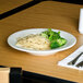 A Homer Laughlin wide rim china soup bowl filled with noodles and broccoli on a table.