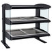 A black and silver Hatco heated countertop display with two shelves holding trays.