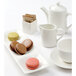 A white Tuxton china creamer on a table with cookies.