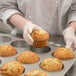 A person in a white coat holding a jumbo pecan roll muffin from a Chicago Metallic muffin pan.