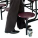 A man in a suit and tie standing next to a National Public Seating mobile cafeteria table with stools.