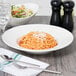 A bowl of pasta with cheese and a salad on a table.