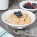 A Tuxton Modena AlumaTux China bowl filled with oatmeal and blueberries on a table.