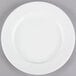 A Tuxton AlumaTux Pearl White china plate with a white rim on a gray surface.