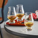 A Stolzle whiskey tasting set with three glasses of brown liquid on a tray.