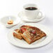 A plate of french toast and a Tuxton white espresso cup filled with coffee on a table.