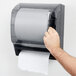 A hand using a Thunder Group black roll towel dispenser to pull a paper towel.