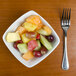 A TuxTrendz Linx china bowl filled with fruit on a table with a fork.